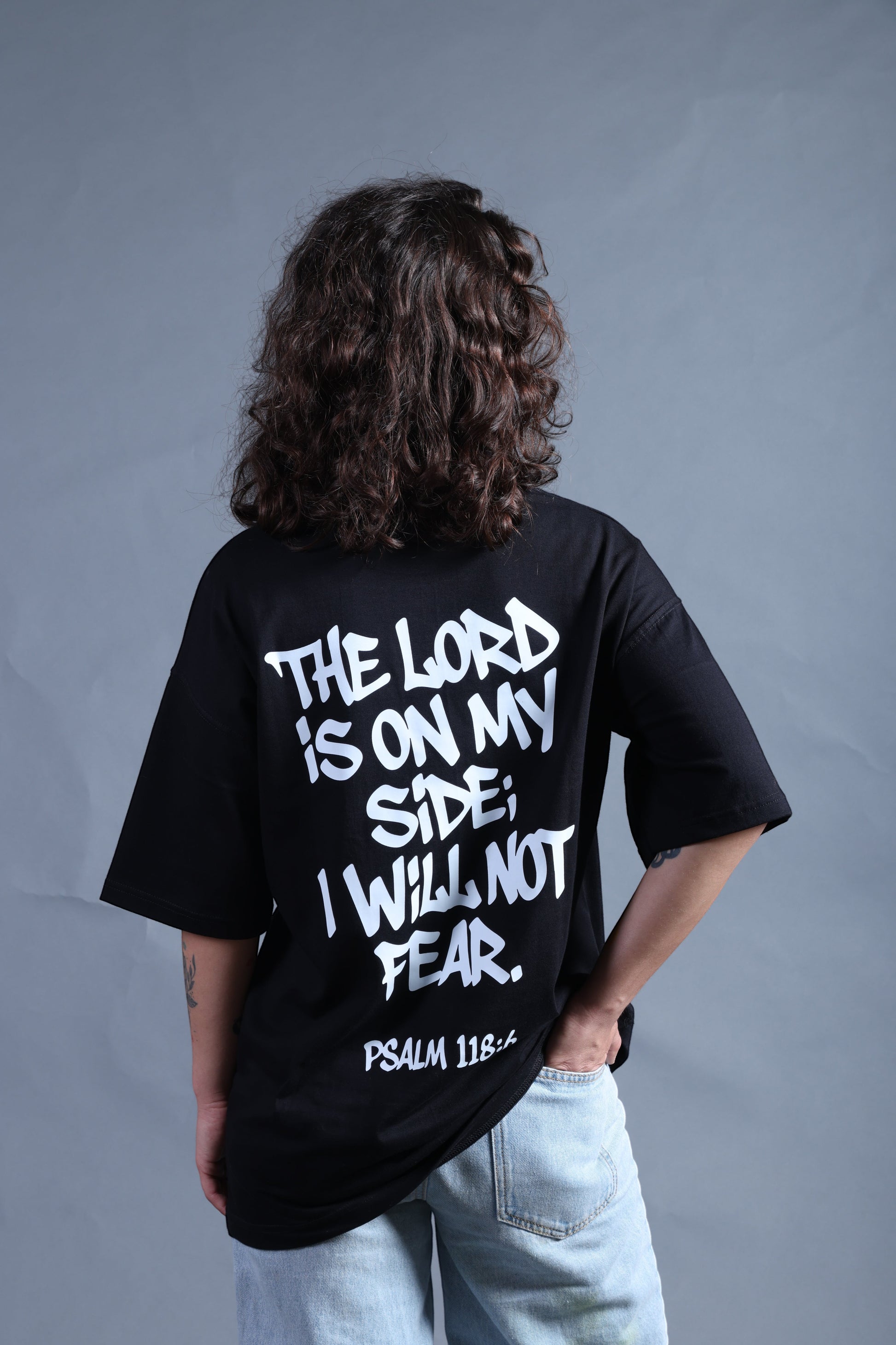 Revel black cotton t-shirt with white graffiti-style text reading "The Lord Is On My Side; I Will Not Fear. Psalm 118:6" on the back.