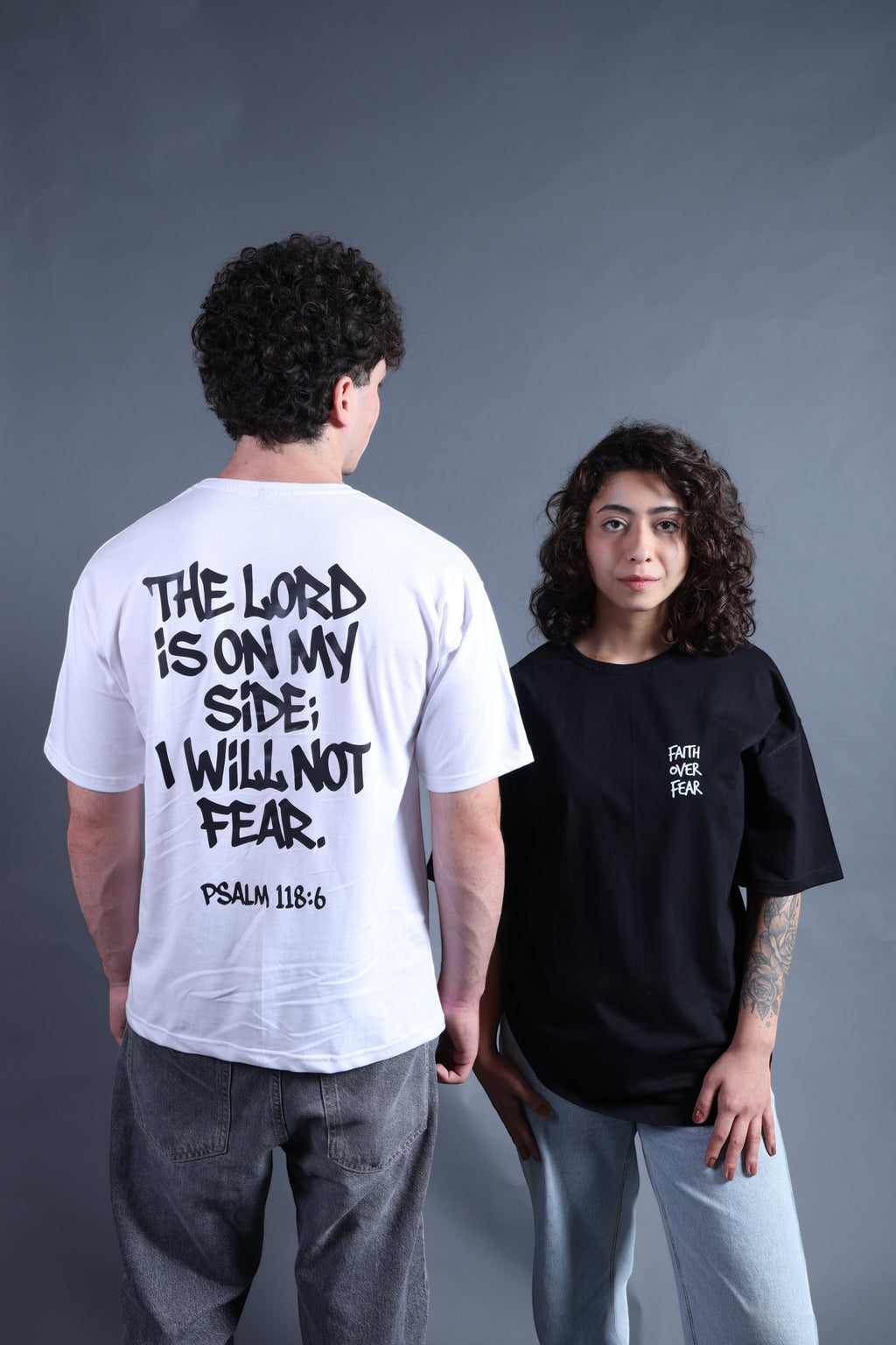 Revel white cotton t-shirt with black text "The Lord Is On My Side; I Will Not Fear. Psalm 118:6" on back. Black t-shirt with "Faith Over Fear" on chest.
